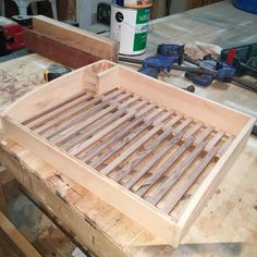 a wooden bed frame sitting on top of a table next to pliers and tools