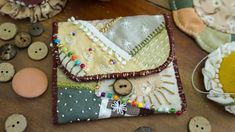 an assortment of buttons and fabric on a wooden table with small purses in the background