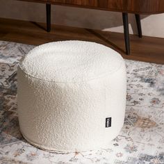 a white round ottoman sitting on top of a rug