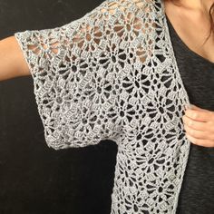 a woman is wearing a lacy crochet shawl