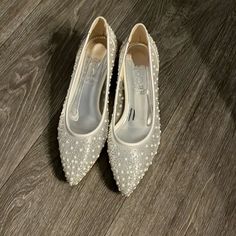 a pair of white shoes with pearls on them