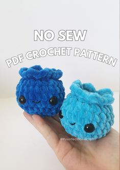 two blue crocheted animals sitting next to each other on a person's hand