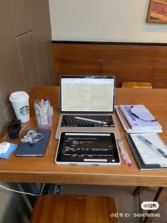 a laptop computer sitting on top of a wooden desk next to a cup of coffee