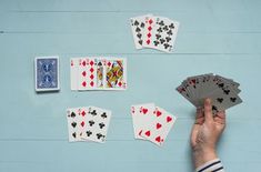 playing cards are being held by a person's hand on a blue surface,