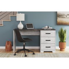 an office desk with a laptop on it and a potted plant next to it