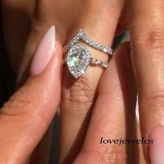 a woman's hand with two engagement rings on top of her fingers and the other hand holding an engagement ring