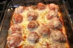 a pan filled with meatballs and cheese on top of a stove