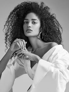 a black and white photo of a woman with curly hair, wearing a white shirt