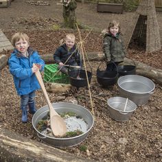 three children are playing in the dirt with buckets and a wooden spatula on it