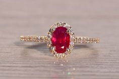 an oval shaped ruby and diamond ring on a wooden surface