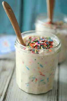 two jars filled with food and sprinkles on top of a wooden table