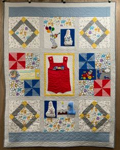 a quilted wall hanging on the side of a wooden floor with an infant's bib and boot