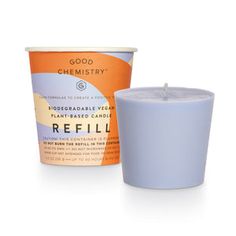 an orange and blue candle next to a cup of refilling cream on a white background