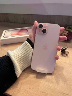 a person holding an iphone in their hand with the back cover up to show it's pink color