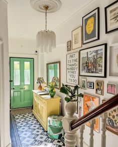 an entry way with pictures on the wall and green door in the background, along with a yellow chest of drawers