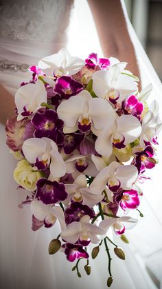 a bride holding a bouquet of purple and white orchids