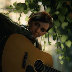 a young man holding a guitar under a tree