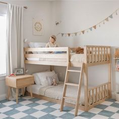 a young child sitting on top of a bunk bed in a room with blue and white checkered flooring