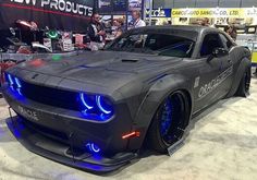 a gray car with blue lights on it's hood at an auto show in front of people