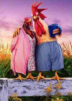 two chickens are standing on a fence with their arms around each other and one is holding a blue mug