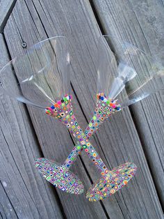 two wine glasses sitting on top of each other in front of a wooden fence with beads