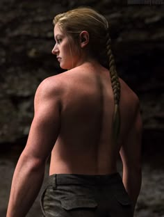 a woman with long hair standing in front of rocks