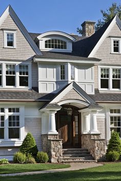 a large house with white windows and stone steps leading to the front door that leads up to the second story