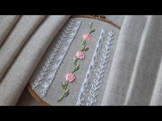 a close up of a embroidery on a piece of cloth with pink flowers and leaves