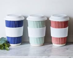 three coffee cups sitting on top of a marble counter