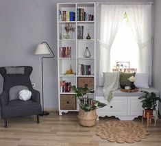 a living room filled with furniture and bookshelves next to a window covered in curtains