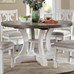 a dining room table with white chairs and a vase full of flowers on the table