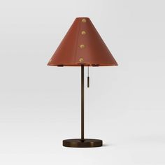 a lamp that is on top of a wooden stand with a red shade over it