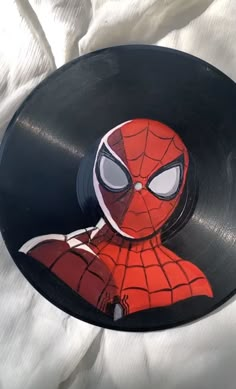 a record player with a spiderman face on it's side sitting on a white sheet