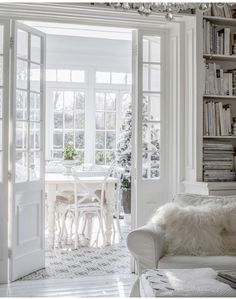 a living room filled with white furniture and a chandelier hanging from the ceiling