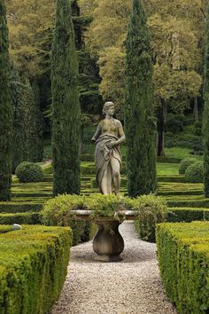 a statue in the middle of a garden surrounded by hedges