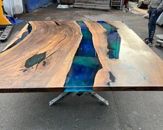 a table made out of wood with blue and green paint on the top is being worked on