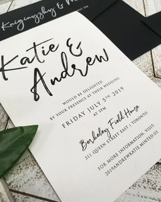 a white and black wedding card with the word kate & andrew written on it next to a green plant