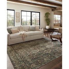 a living room with a large rug and two chairs in front of the couches