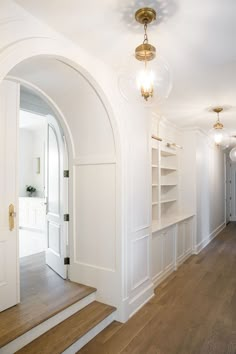 a hallway with white walls and wooden floors