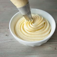 a white bowl filled with cream on top of a wooden table