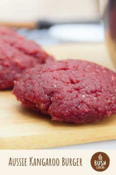 two hamburger patties sitting on top of a wooden cutting board