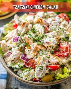 a close up of a salad in a bowl with dressing on top and the words taziki chicken salad above it