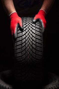 a man in red gloves is holding a tire with both hands and his feet on it