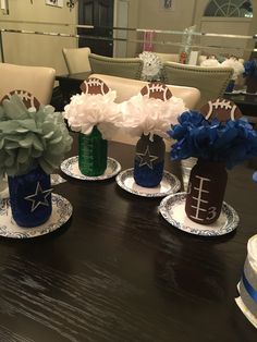 three vases with flowers and football decorations on them sitting on a dining room table