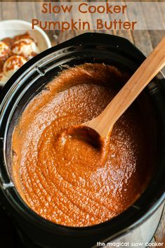 slow cooker pumpkin butter in a crock pot with a wooden spoon on the side