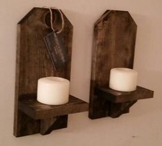 two rustic wooden candle holders with white candles on the top and tags attached to them