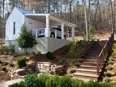 a car is parked on the porch of a house in the woods with steps leading up to it