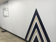 an office hallway with white walls and blue and gold lines on the wall, along with a black vacuum cleaner