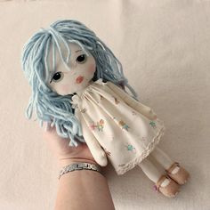 a hand holding a doll with blue hair