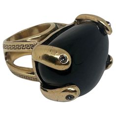 THIS Gianni Versace cocktail ring features a bold design with a large, oval-shaped black agate (as the centerpiece. The black agate is smooth and polished, adding a striking contrast to the **gold-tone metal setting**, which has an intricate and distinctive Versace style. The ring’s design is bold, with **four thick, claw-like prongs** securely holding the stone in place. These prongs are embellished with small, clear stones, adding a subtle sparkle to the design. The ring band itself has an ope Italian Ring, Cocktail Ring Designs, Yellow Gold Cocktail Ring, Versace Style, S Aesthetic, Vintage Cocktail Ring, 1990s Fashion, Gold Cocktail Ring, Gold Cocktail